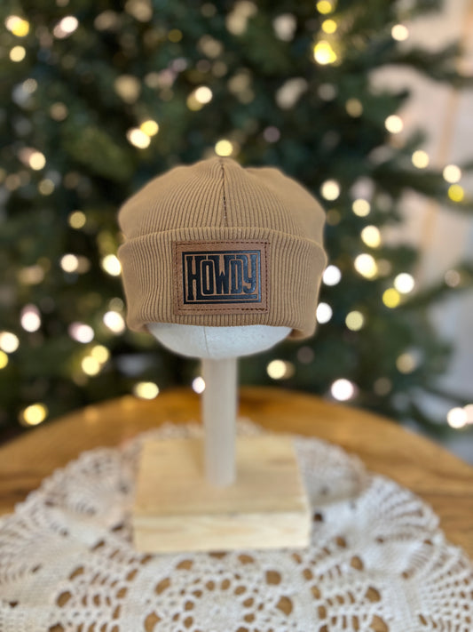 Beige cap on a mannequin head with 'HOWDY' logo in front of a decorated Christmas tree.