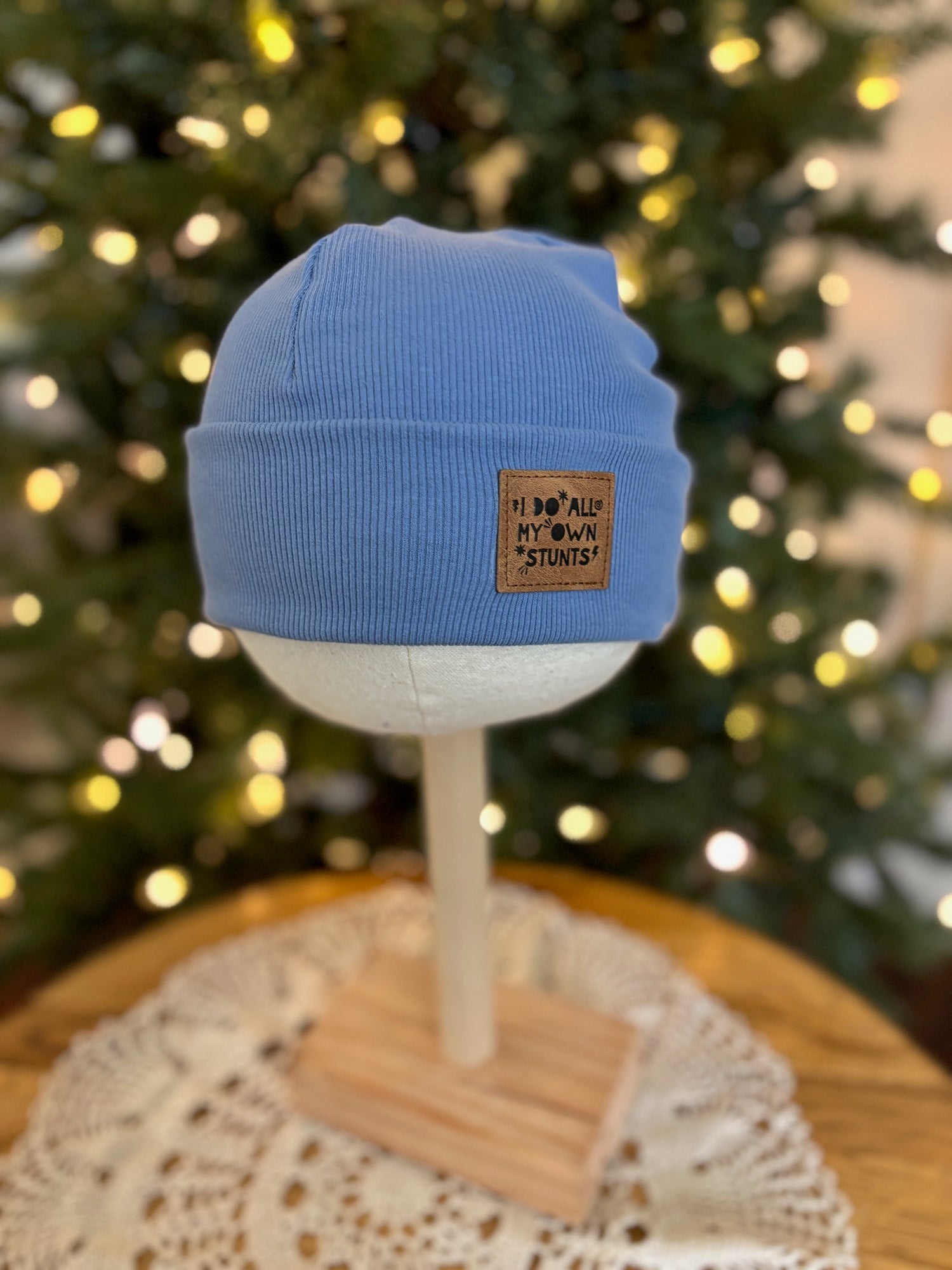 Blue beanie on a mannequin head with a Christmas tree in the background