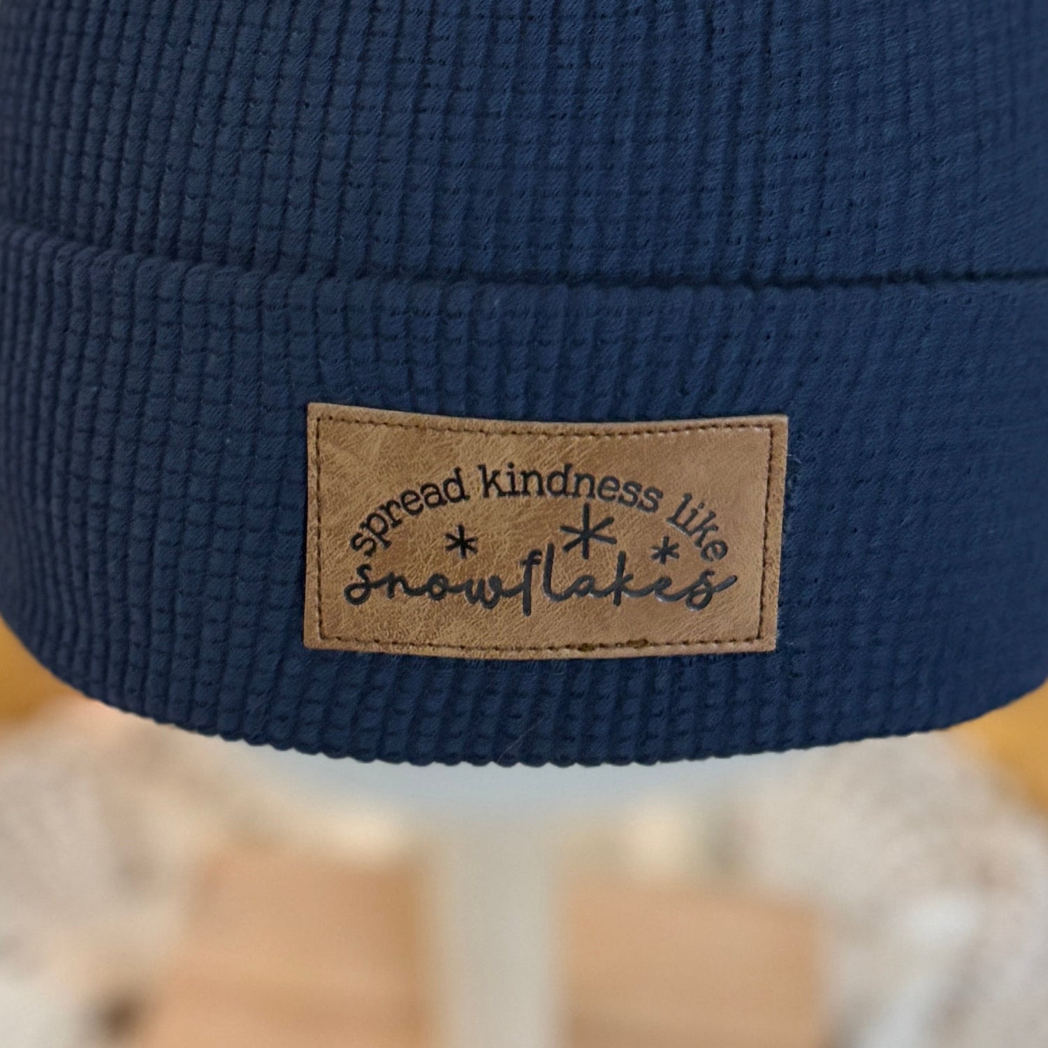 Blue beanie with a pom-pom on a mannequin head in front of a Christmas tree.