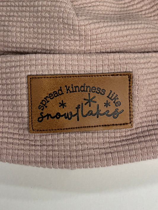 Pink beanie with fur pom-pom and brand label on a white background