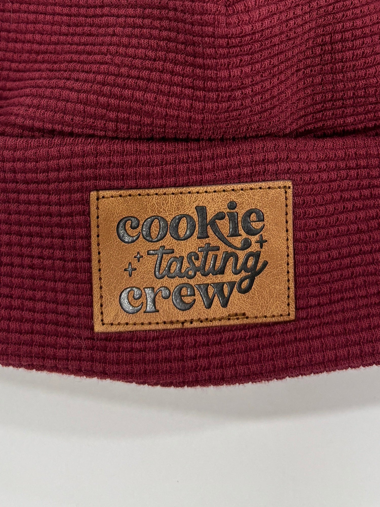 Maroon knit beanie with a fur pom-pom and brand label on a white background