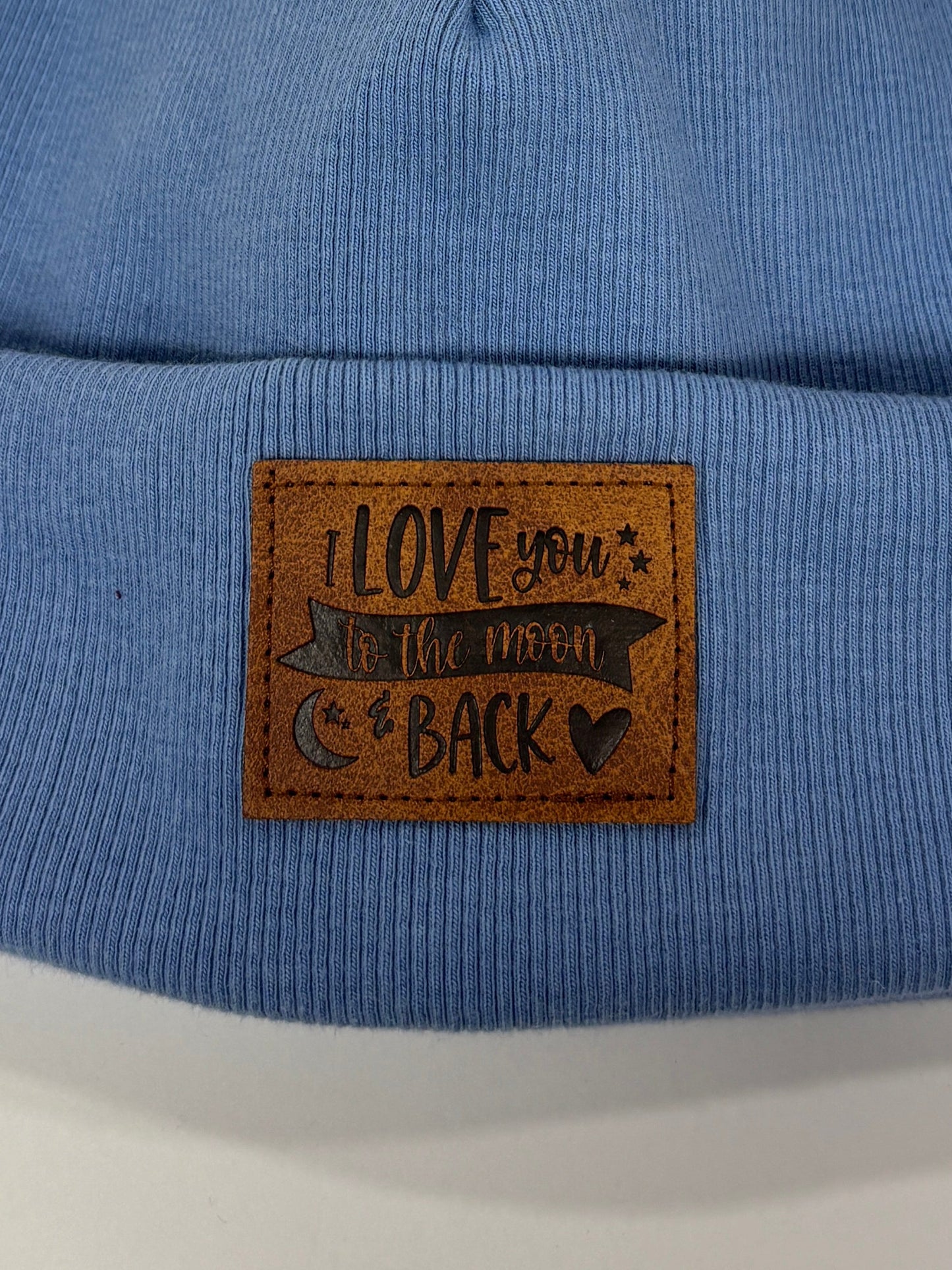 Blue beanie with a pom-pom and a brand label on a white background